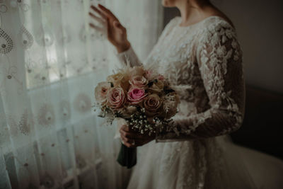 Midsection of woman holding rose at home