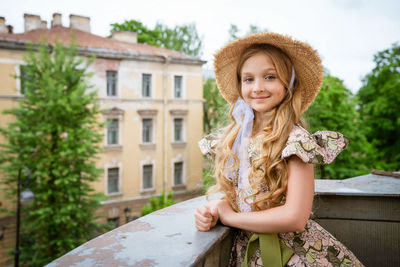 Little girl in dress and hat posing on the balcony