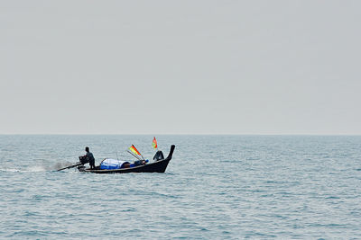 People in boat on sea against clear sky