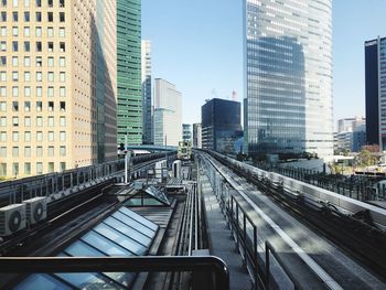 Railroad tracks amidst buildings in city against sky