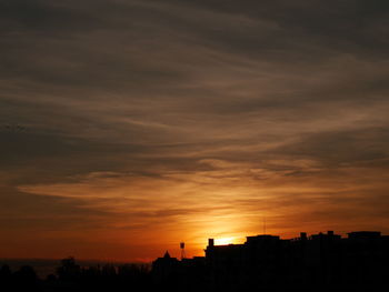 Silhouette buildings against sky during sunset
