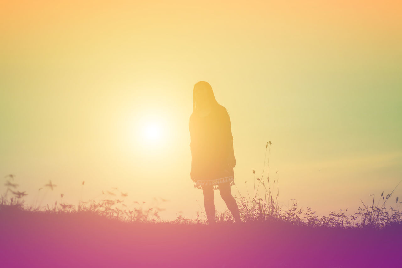 REAR VIEW OF SILHOUETTE WOMAN STANDING ON FIELD AGAINST SKY