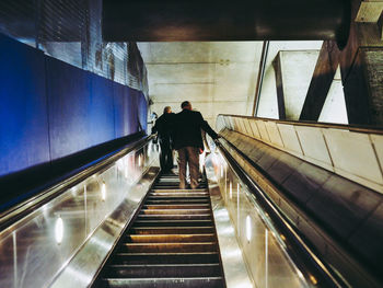 Rear view of people walking on escalator