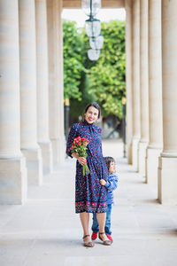 Portrait of elegant woman in a blue dress posing next to a city building