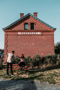 People on wall by building against sky