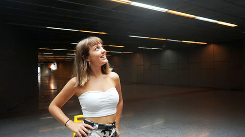 Teenage girl looking away while standing in illuminated underground walkway