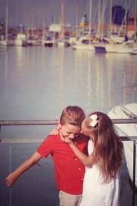 Sister embracing brother while standing by railing