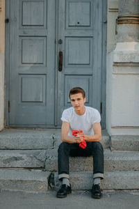 Full length of boy sitting by door