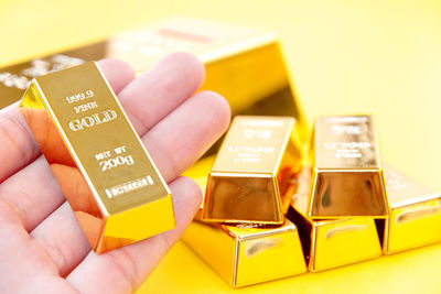 Close-up of hand holding gold ingot at table