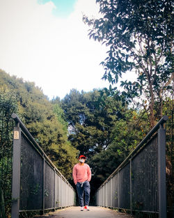 Man standing by railing against sky