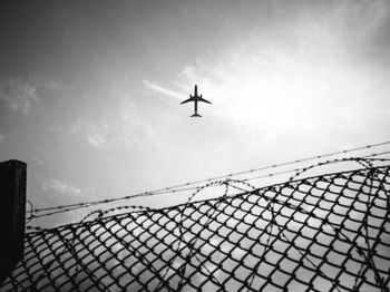 Low angle view of silhouette airplane against sky