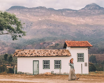 Woman walking near old house with serra do caraça in background