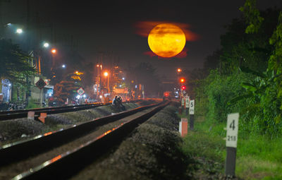 Illuminated railroad tracks against sky at night