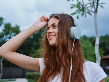 Portrait of smiling young woman with eyes closed against sky