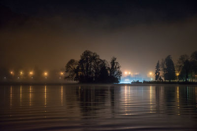 Scenic view of lake against sky at night with smog