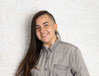 Portrait of young woman standing against wall