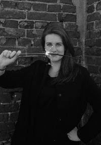 Portrait of young woman standing against wall