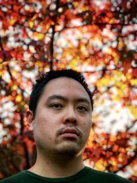 Portrait of young man with autumn leaves at sunset.