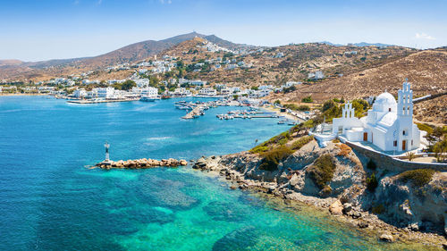 Buildings by sea on mountains during sunny day