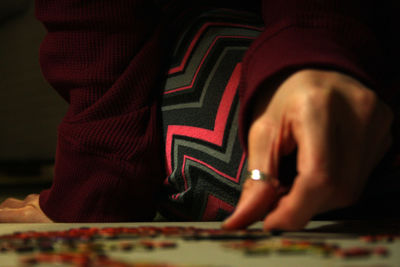 Midsection of woman solving puzzle on floor