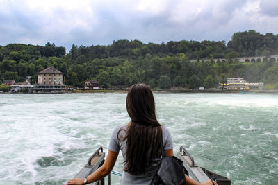 Rear view of woman standing on boat over rhine river against trees