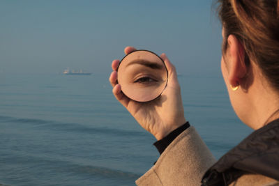 Woman looking into a round mirror holding in her right hand