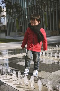 Full length of boy looking at fountains in city during winter