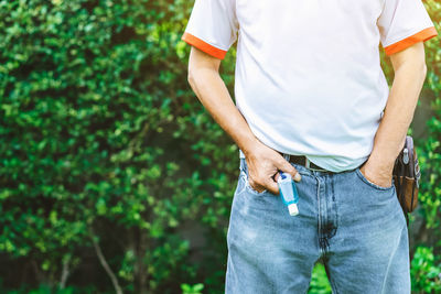 Midsection of man with hand in pocket standing against plants