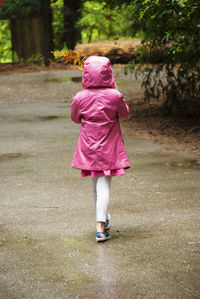 Rear view of girl walking on wet footpath during rainy season