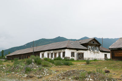 Houses on field by mountains against clear sky