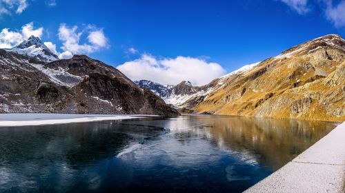 Scenic view of lake and snowcapped mountains against blue sky