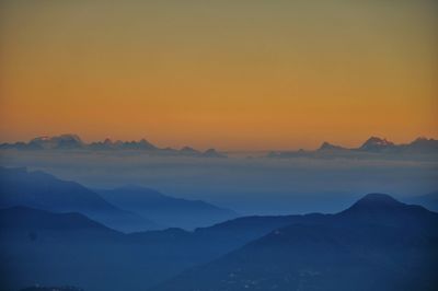 Scenic view of silhouette mountains against orange sky