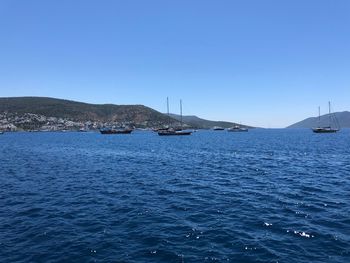 Sailboats in sea against clear blue sky