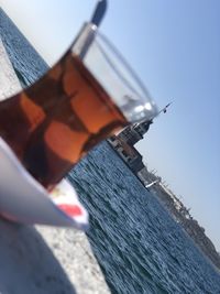 Close-up of hand holding sailboat against sea