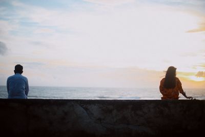 Rear view of man and woman looking at sea against sky