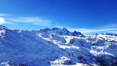 Scenic view of snowcapped mountains against blue sky