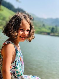 Side view of smiling girl sitting by lake