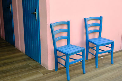 Empty chairs and tables against blue wall at home