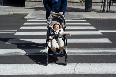 Father with baby in baby stroller crossing road in city