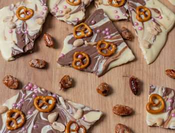 White and brown chocolate prepared for a broken chocolate topped with pretzel, sugar pearls and nuts