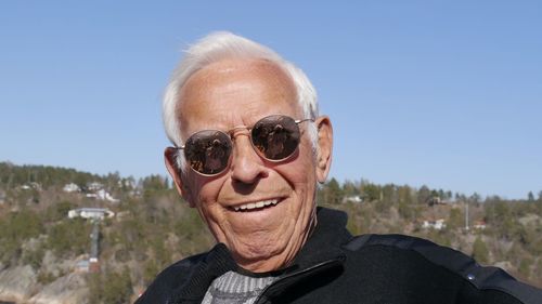 Portrait of smiling senior man in sunglasses against sky