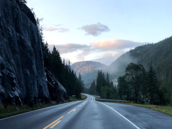 Road leading towards mountains against sky