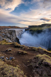 View of waterfall against cloudy sky