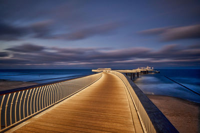 Pier on beach against sky