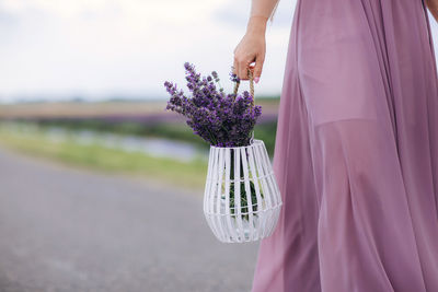 Midsection of woman standing by purple flowering plant