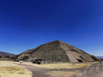 Built structure on landscape against blue sky