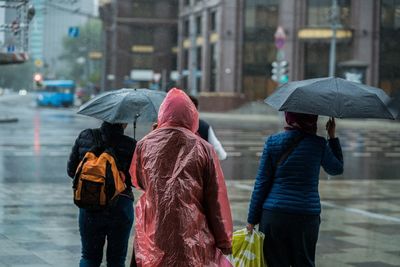 Rear view of people walking on wet road during rainy season