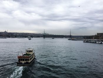 View of suspension bridge over river against cloudy sky