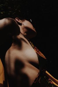 Midsection of young woman holding cigarette against black background