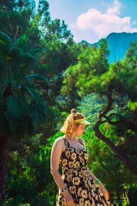 Woman standing by tree against plants